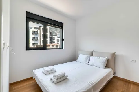 Bright bedroom with a double bed and a window overlooking buildings. - image 16