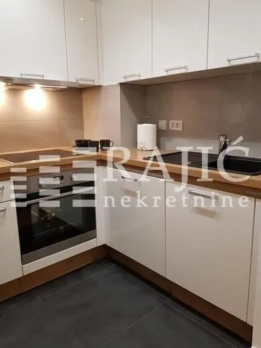 Modern kitchen with white cabinets and built-in appliances.