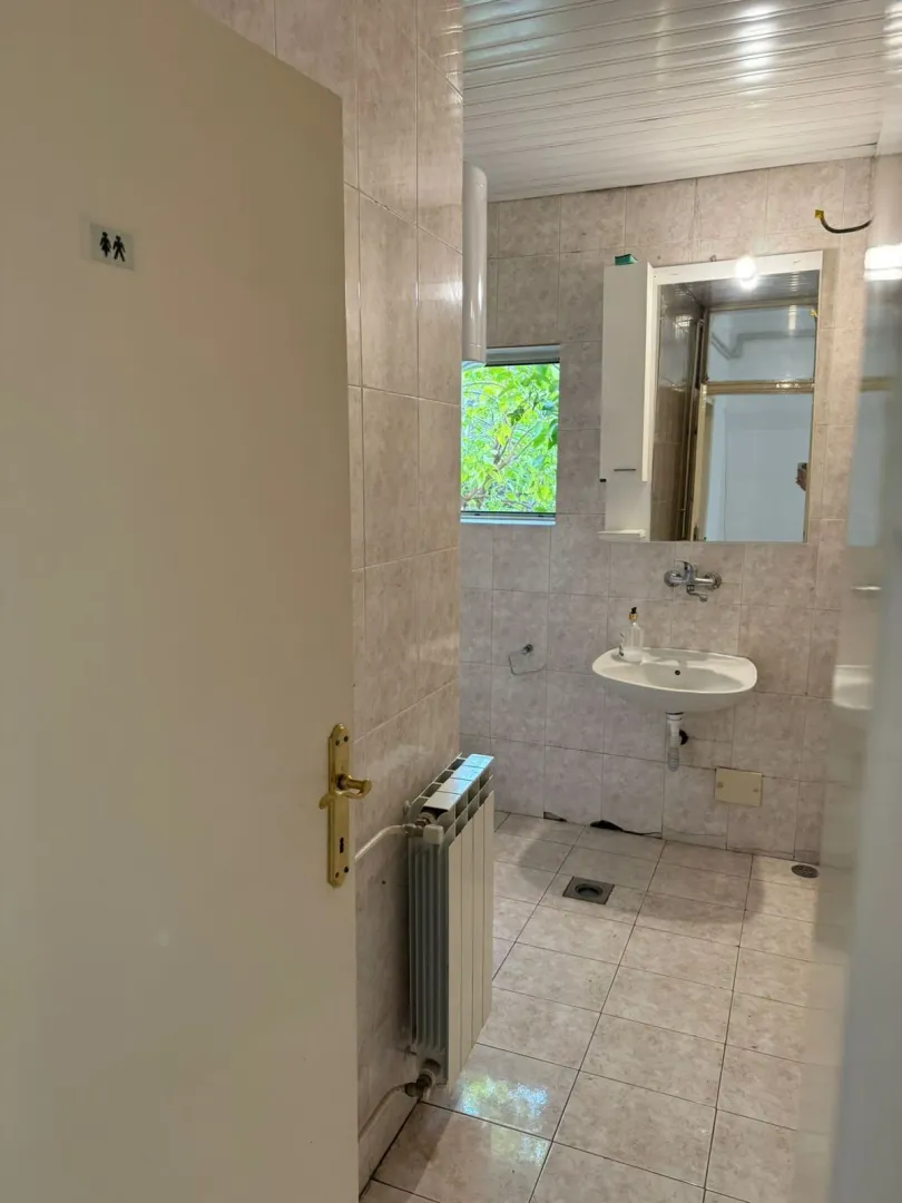 A bathroom with a sink and mirror seen through an open door.