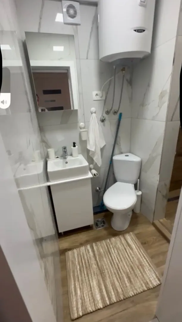 Small bathroom with a washbasin, toilet, and mounted water heater.