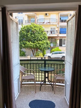 Namješten balkon sa stolom i stolicama i pogledom na dvorište i okolne zgrade. - image 2