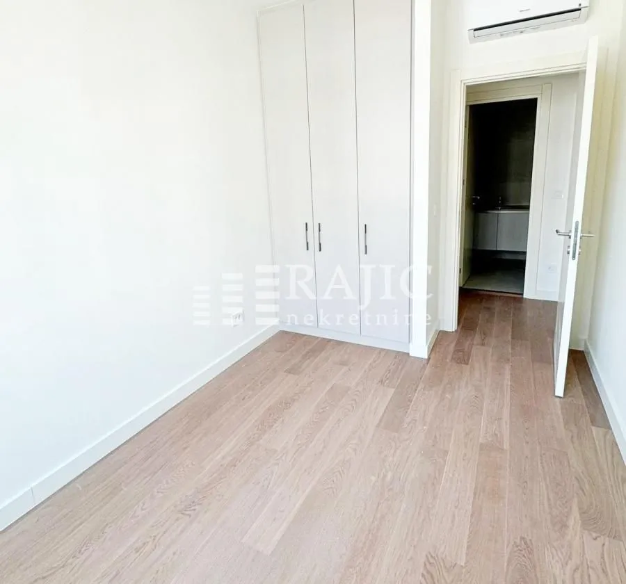 Empty bedroom with a built-in wardrobe and wooden flooring.