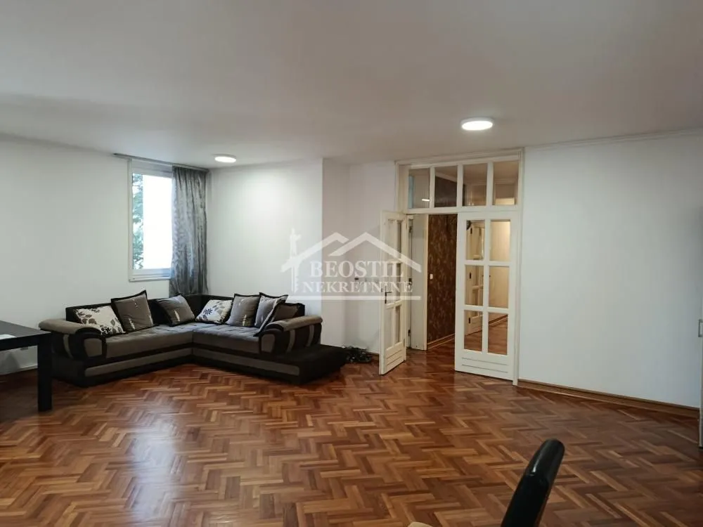Living room with a corner sofa and wooden parquet flooring.