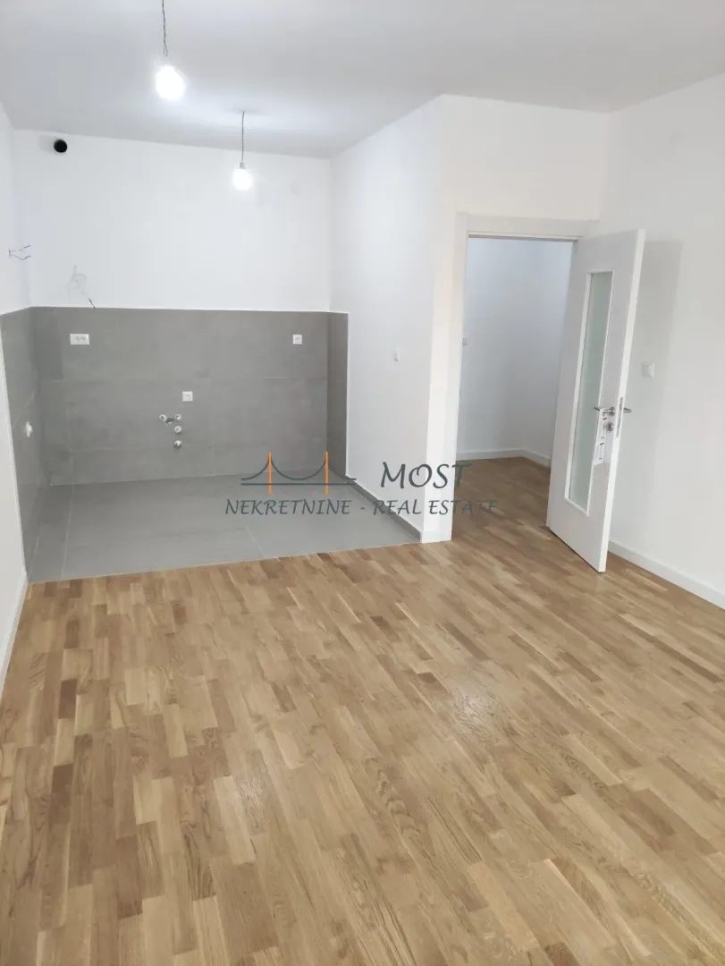 Empty kitchen with grey and white walls and wooden flooring.