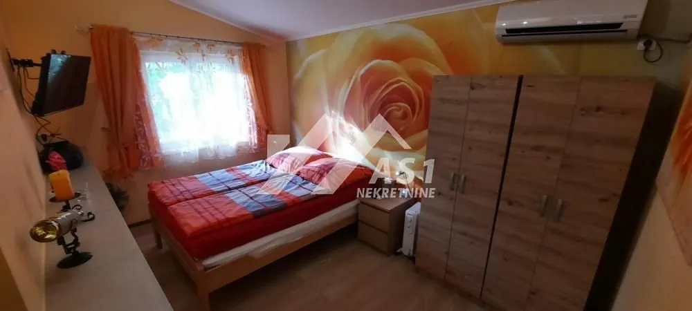 Nameštena spavaća soba sa bračnim krevetom i ormarom.