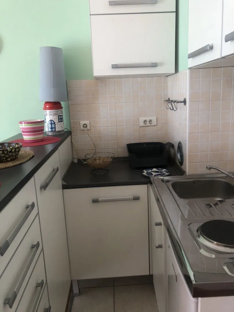 Small kitchen with white cabinets and light-colored tiles.
