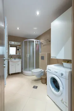 Kupatilo opremljeno tuš kabinom, umivaonikom, WC šoljom i veš mašinom. - image 8