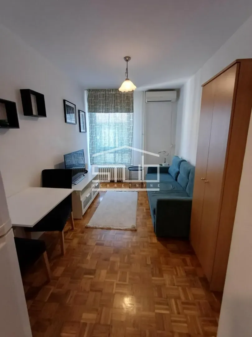 Living room with a sofa, TV, and dining table.