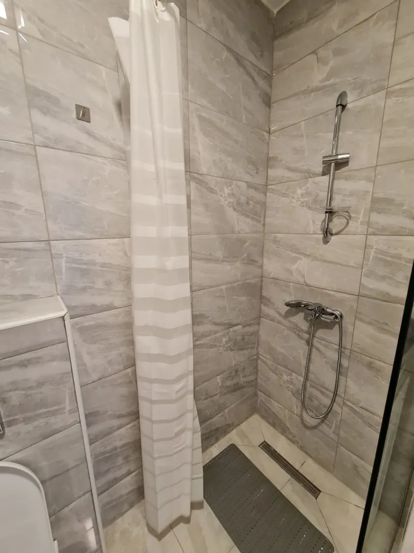 Bright bathroom featuring a shower cabin with grey tiles.