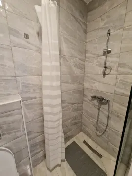 Bright bathroom featuring a shower cabin with grey tiles. - image 10