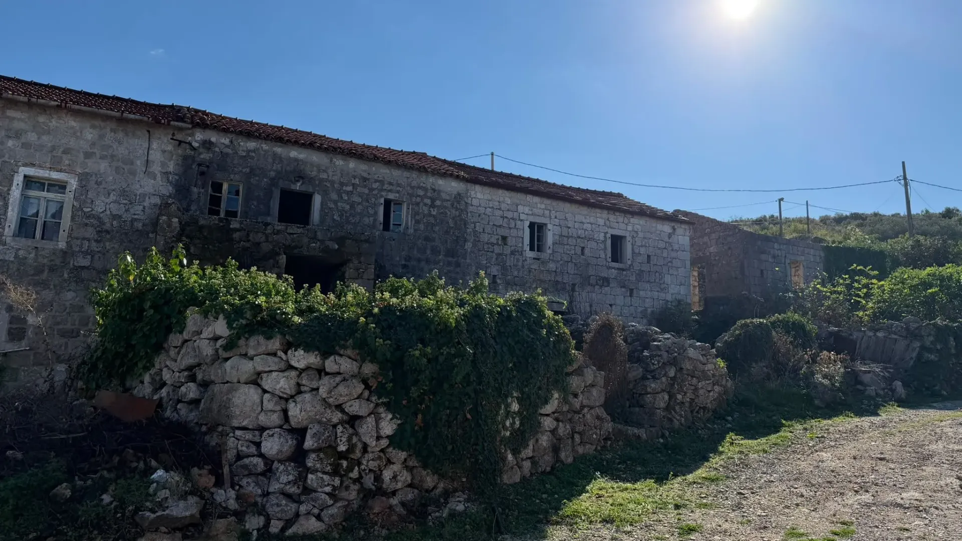 Pogled na staru kamenu kuću sa dvorištem.
