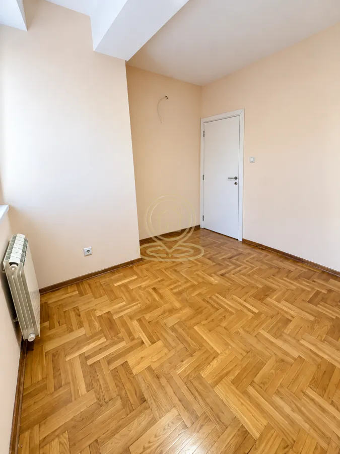 Empty room with parquet flooring and a white door.