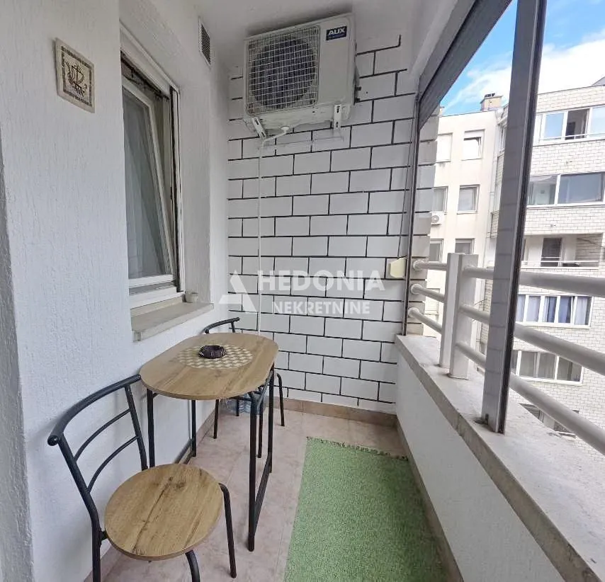 Manji zatvoreni balkon sa trpezarijskim stolom i klima uređajem.
