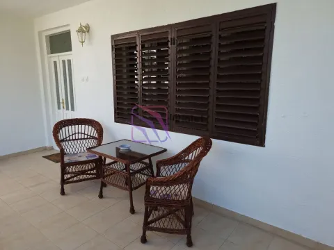 Covered terrace with wicker furniture and dark shutters on the wall. - image 10