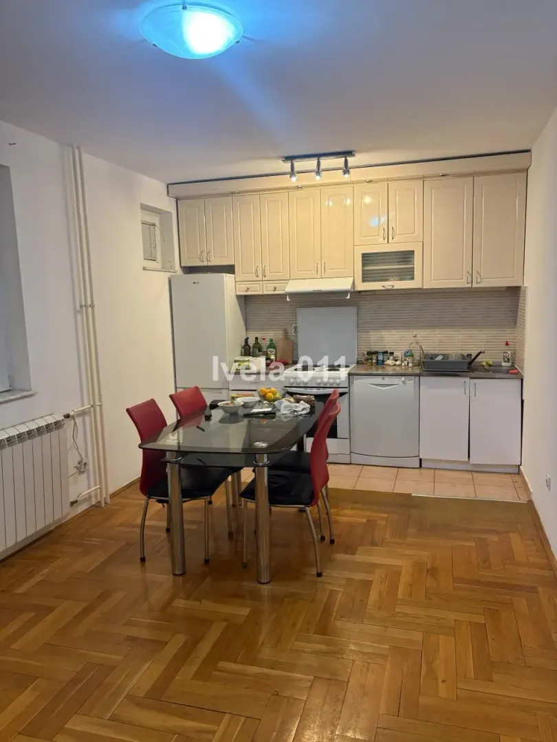 Kuhinja sa trpezarijom i drvenim podom.