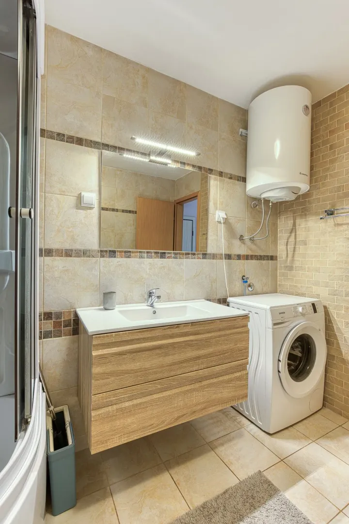 Bathroom with a washbasin, shower cabin, and washing machine.