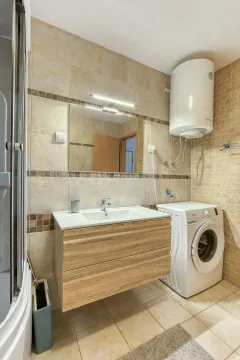 Bathroom with a washbasin, shower cabin, and washing machine. - image 2