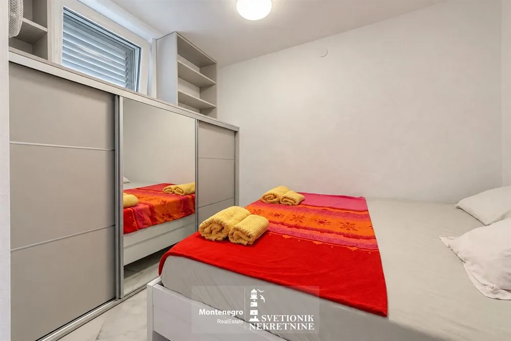 Spavaća soba sa krevetom, garderoberom sa ogledalom i ugradnim policama.
