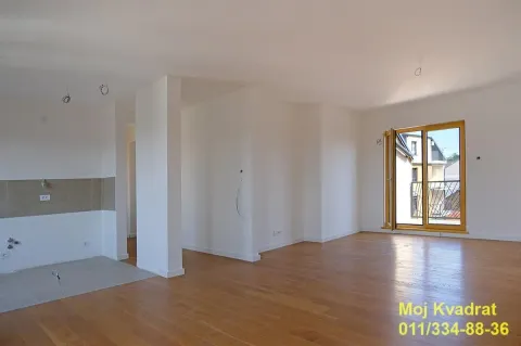 Prazna neopremljena prostorija sa drvenim podom i balkonskim vratima. - image 2