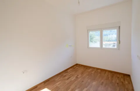 Prazna soba sa bijelim zidovima, drvenim parketom i prozorom. - image 9