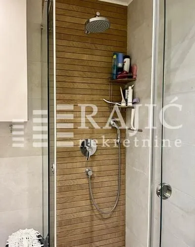 Modern walk-in shower with wooden wall paneling.