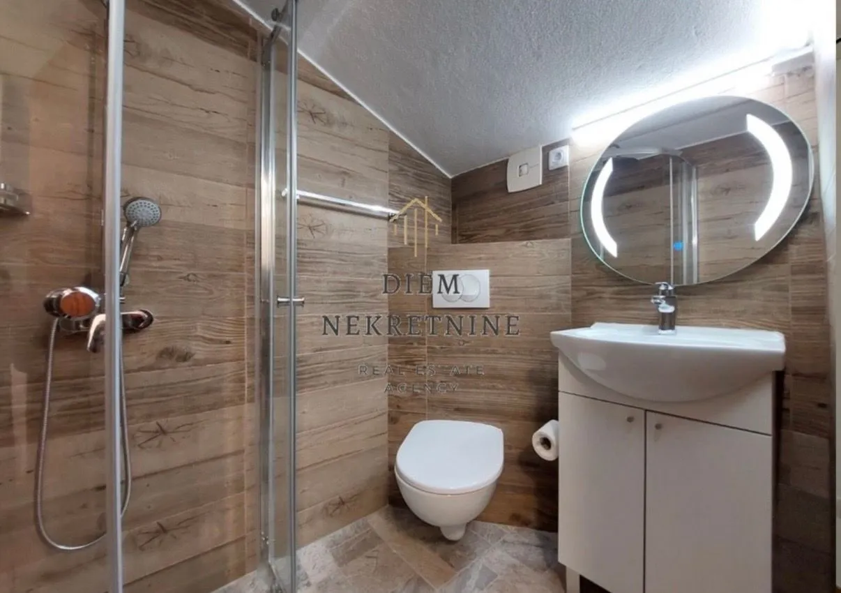 Moderne kupatilo sa tuš kabinom, umivaonikom i wc šoljom.