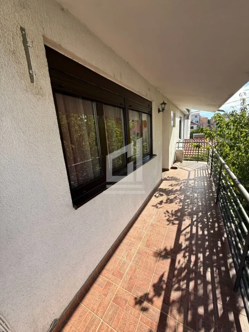 Spacious covered terrace with ceramic tiles and a railing.