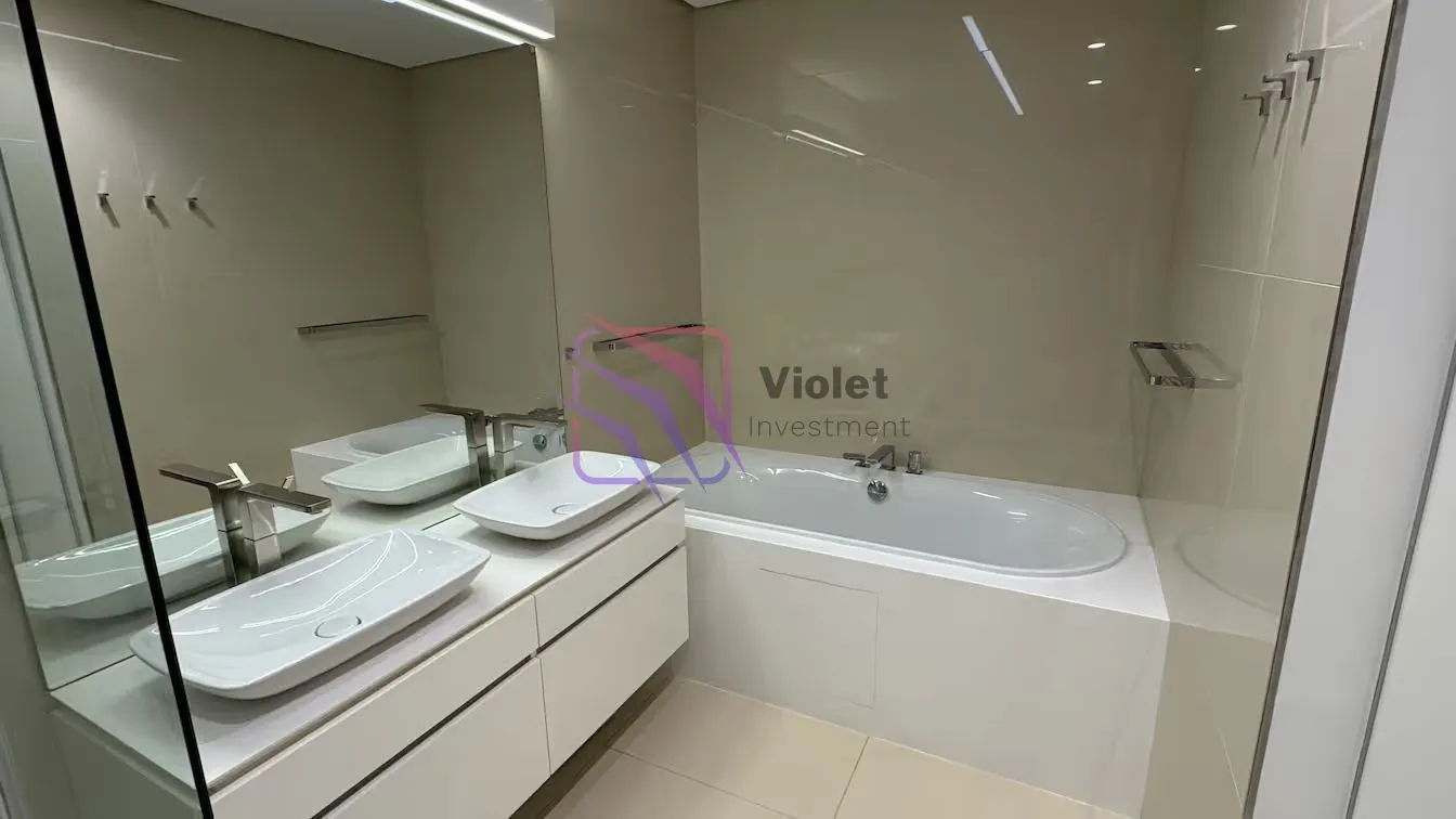 Moderne kupatilo sa bijelim umivaonikom i kadom u bež tonovima.