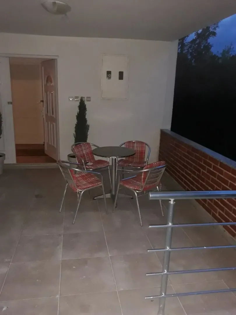 Natkrivena terasa sa okruglim stolom i četiri stolice.