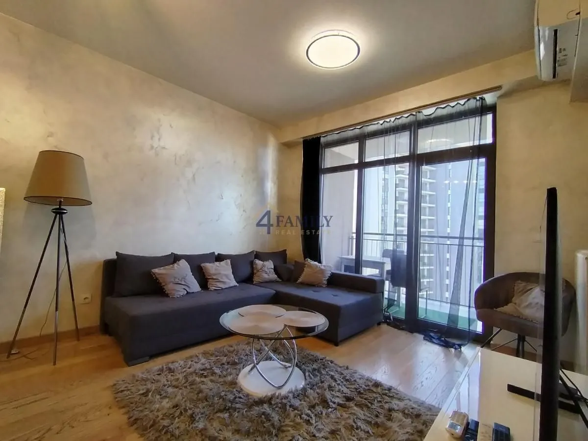 Living room with a sectional sofa, coffee table, and balcony access.