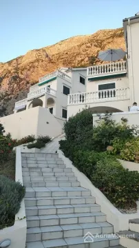 Spoljašnji pogled na višespratnu kuću sa stepeništem i terasama u podnožju planine. - image 14