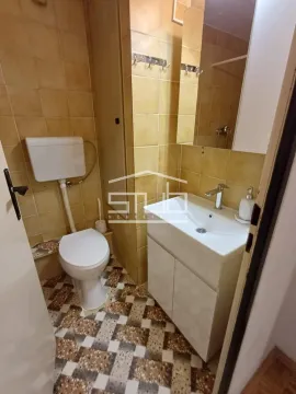 Small bathroom with a sink, toilet, and brown-toned tiles. - image 7