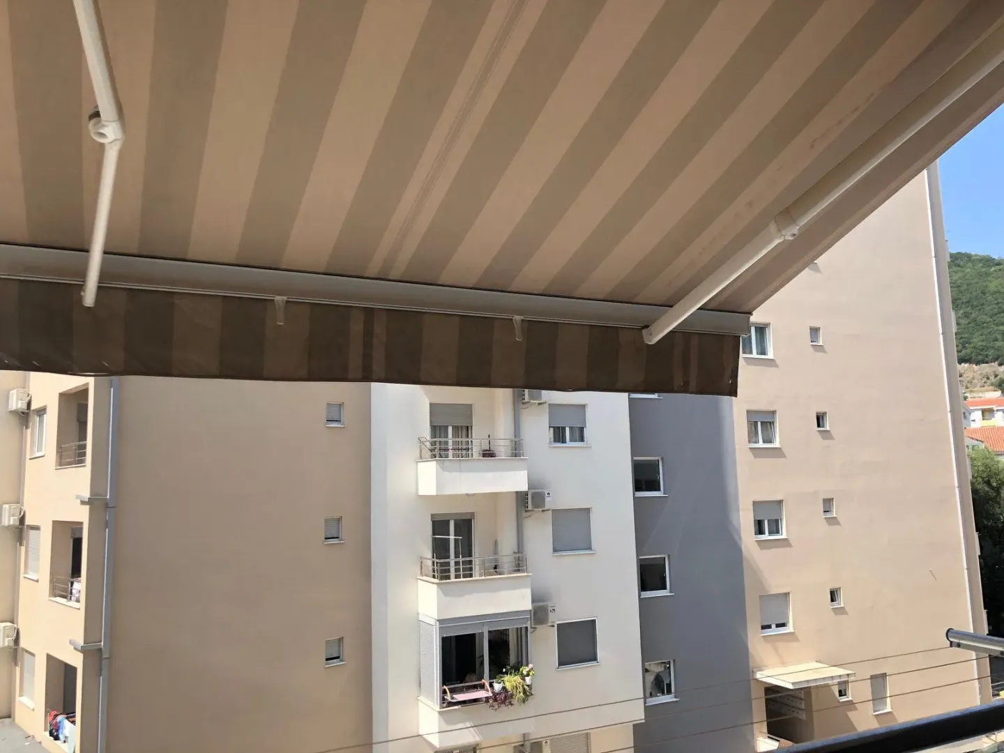 View from a balcony with an awning towards surrounding residential buildings.