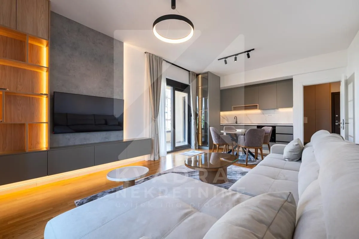 Modern living room with a sofa, TV, and an adjoining dining area.