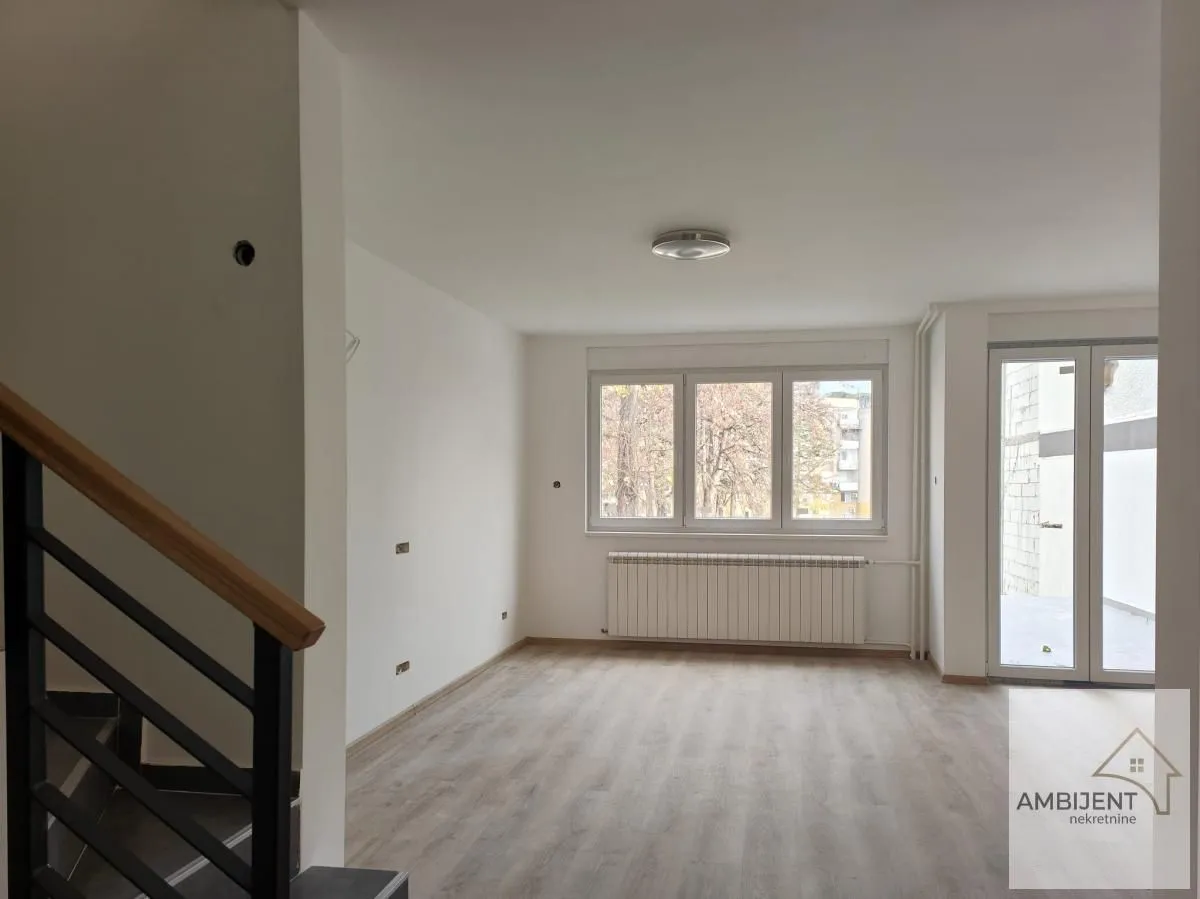 Empty bright room with windows and a staircase in the apartment.