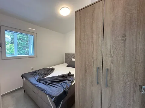 Manja spavaća soba sa bračnim krevetom i velikim drvenim garderoberom. - image 4