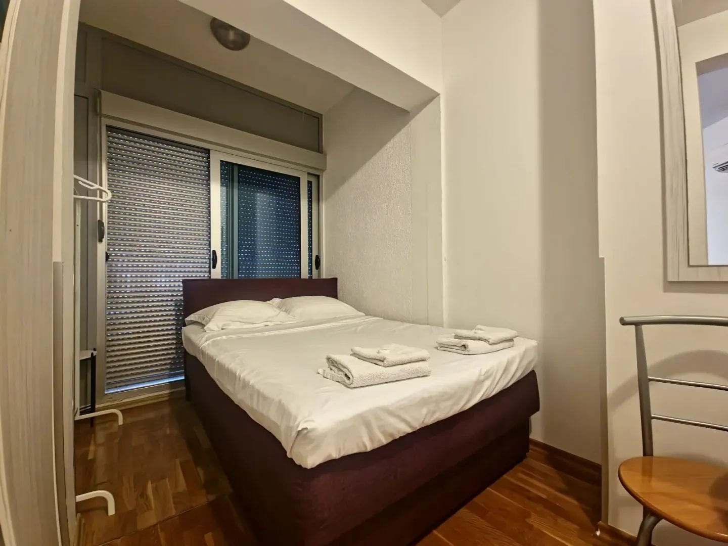 Bedroom with a double bed and a window with blinds.