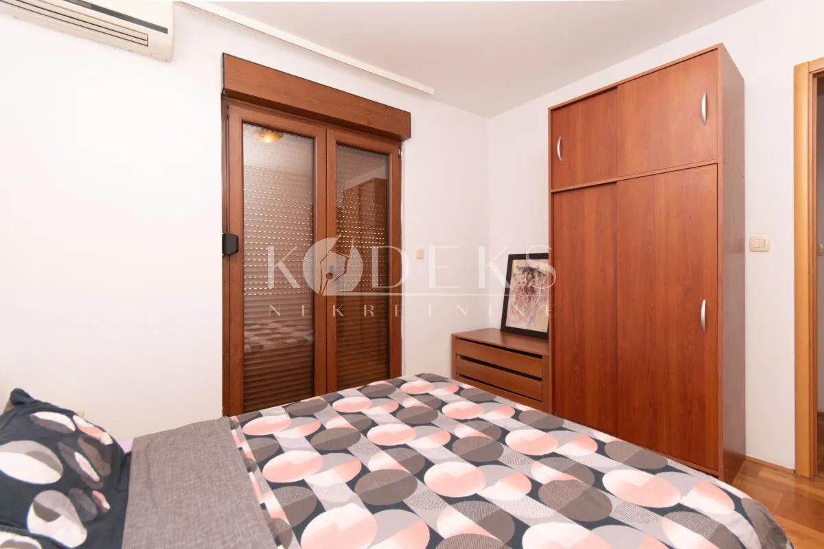 Furnished bedroom with a double bed, wooden wardrobe, and balcony doors.