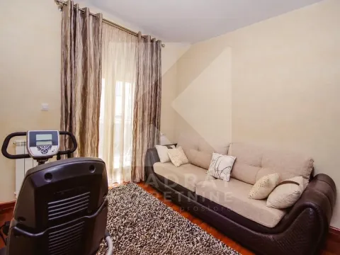 Living room with a sectional sofa, rug, and stationary bicycle near the window. - image 11