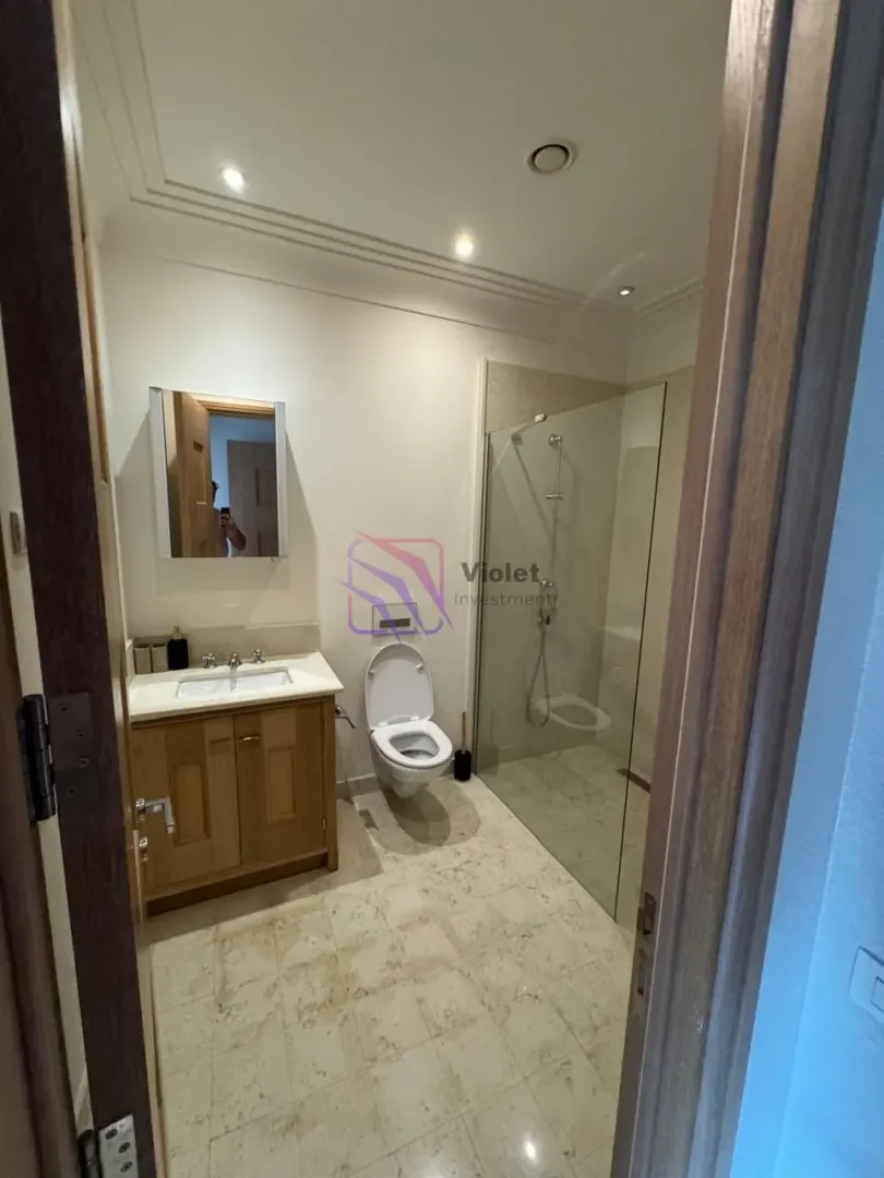 Modernly equipped bathroom with a washbasin, toilet, and walk-in shower.