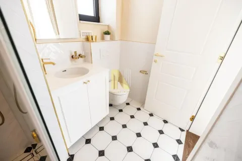 Modern bathroom with white cabinetry, gold fixtures, and black-and-white flooring. - image 8