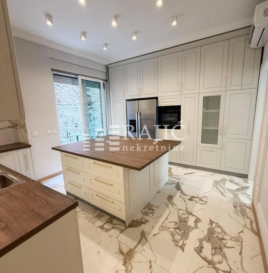 Modern kitchen with white cabinetry, an island, and marble flooring.