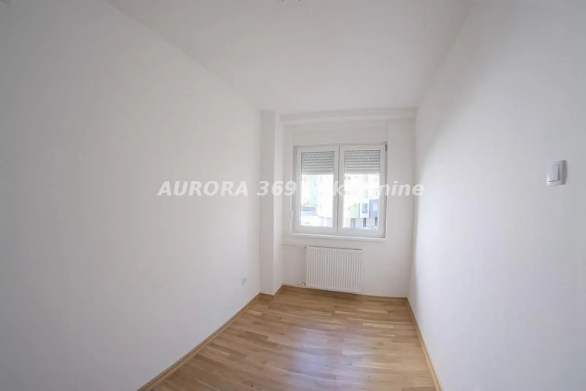 Empty room with white walls, hardwood flooring, and a single window.