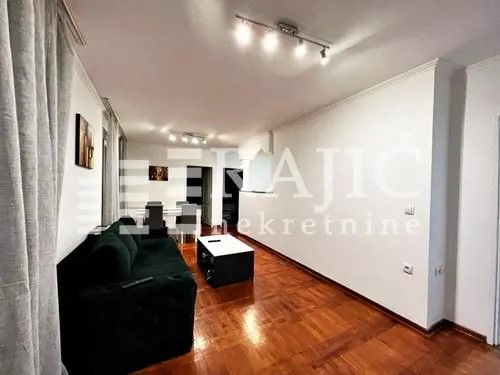 Living room with a sofa and dining area in the background.
