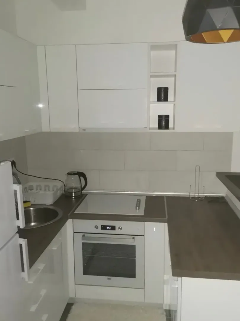 Small modern kitchen with white cabinets and built-in appliances.