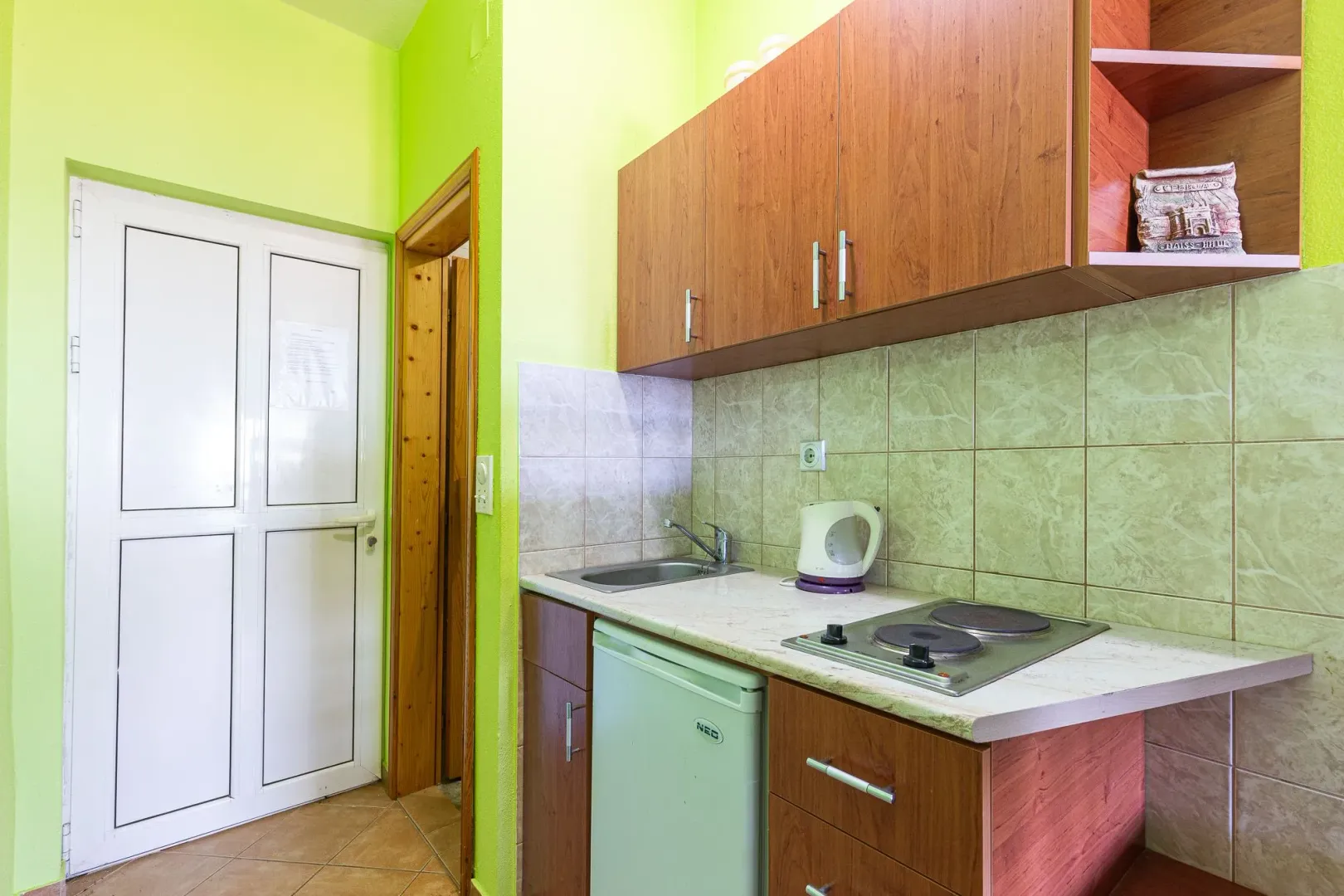Manja kuhinja sa drvenim elementima, sudoperom i ugrađenom pločom za kuvanje.