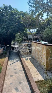 Paved courtyard with a pathway, stone wall, and greenery in the yard of the house. - image 2