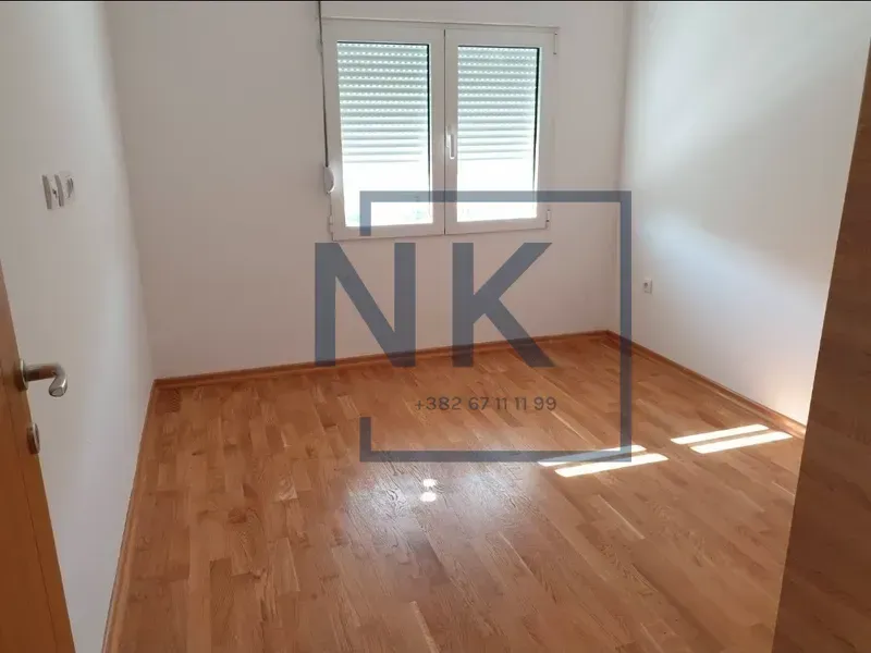 Prazna soba sa parketom i prozorom.