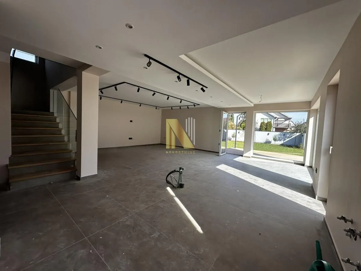 Spacious unfurnished living room with a staircase and access to the yard.