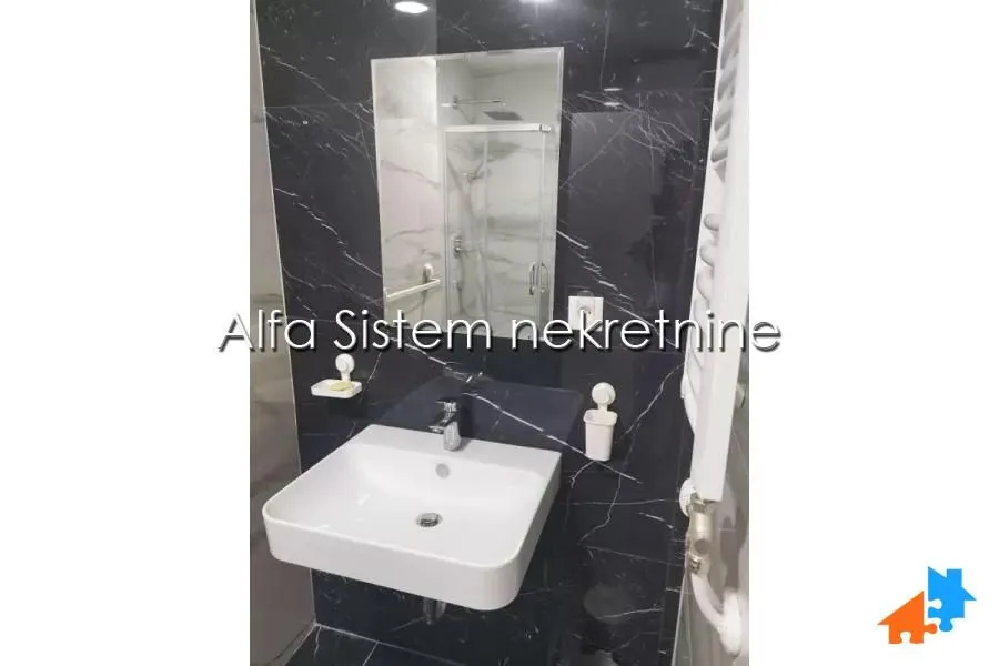 Moderno kupatilo sa umivaonikom i crnim zidnim pločicama.